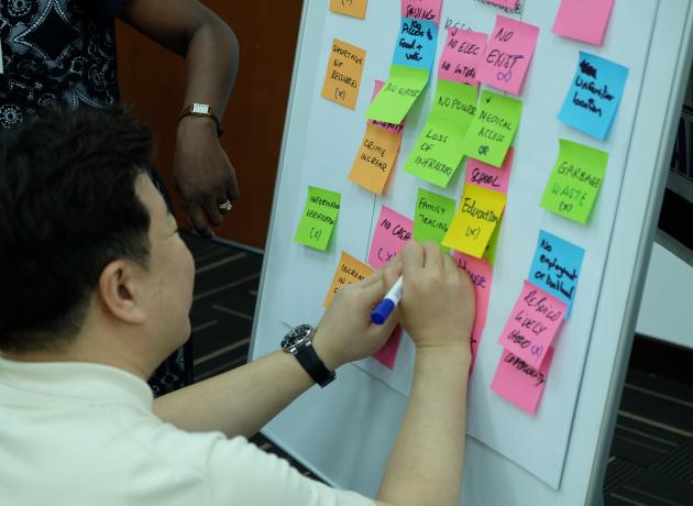 A man adds a sticky note to a flipchart of sticky notes