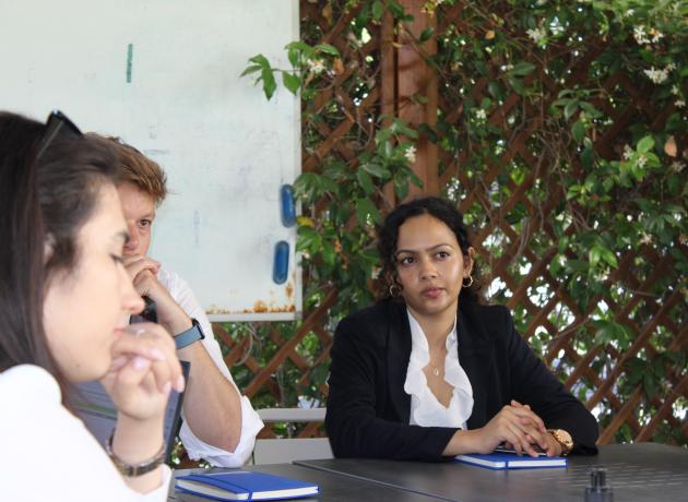 UNAA staff listen to an engaging discussion sitting around a table