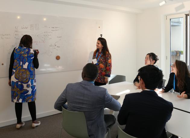 Colleagues gather around a white board during a meeting