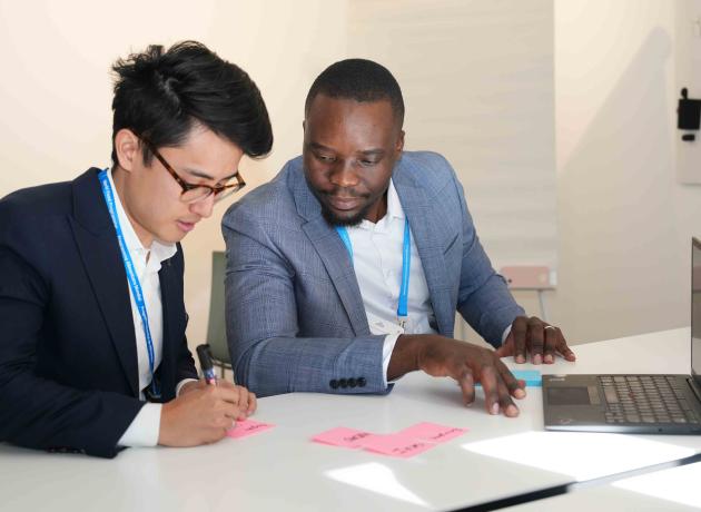 Staff working in an office at a laptop, writing on sticky notes 